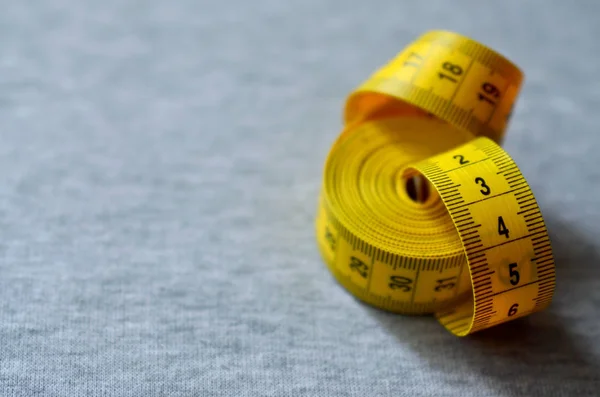 Ruban à mesurer jaune repose sur un tissu tricoté gris — Photo