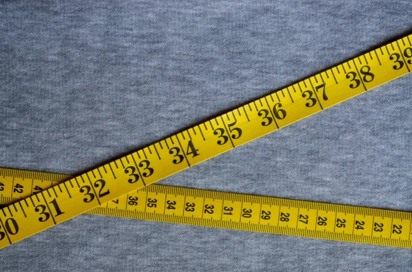 Nastro di misurazione giallo si trova su un tessuto a maglia grigio — Foto Stock