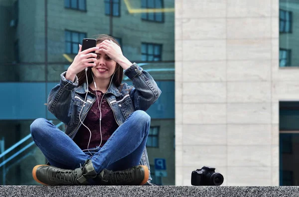 Uma fotógrafa usa um smartphone e senta-se em um parapeito de granito — Fotografia de Stock