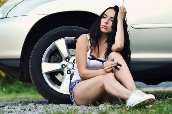 Jong en sexy meisje met spanner dicht bij een zilveren auto — Stockfoto