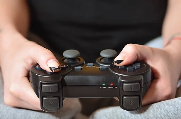 Moderno controlador de juego negro en manos de una joven sentada — Foto de Stock