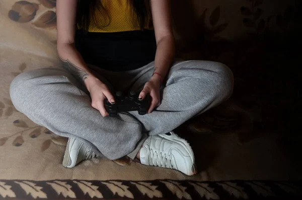 在灰色的裤子的年轻女孩拥有黑色的现代游戏操纵杆与大量的用于管理视频游戏的按钮 通过视频游戏青年休闲的概念 — 图库照片