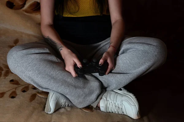 一个年轻的白人女孩 坐在沙发上 玩视频游戏使用现代的黑色操纵杆身体一些片段 游戏控制器在女性手中的特写图片 — 图库照片