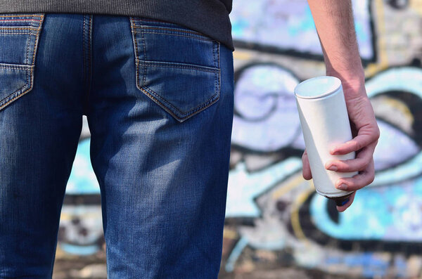 Вид сзади на парня, рисующего стену аэрозольной краской
