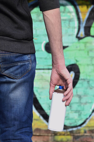 Вид сзади на парня, рисующего стену аэрозольной краской
