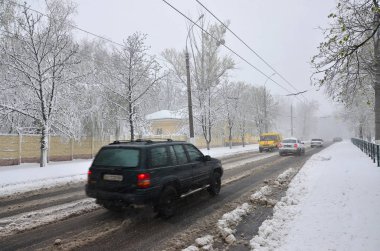 Kharkov, Ukrayna - 19 Nisan 2017: Beklenmeyen hızlı kar yağışı Nisan Kharkiv sokaklarda. Nisan ortasında karla kaplı yolda araba trafik