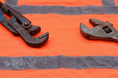 Ayarlanabilir ve boru anahtarı bir turuncu sinyal işçi gömlek arka planı. Natürmort onarım, tren veya sıhhi tesisat işleri ile ilgili