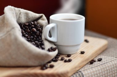 Kahverengi kahve çekirdekleri ve beyaz bir fincan sıcak kahve l tam bir çanta