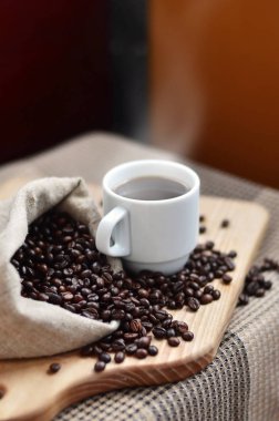 Kahverengi kahve çekirdekleri ve beyaz bir fincan sıcak kahve l tam bir çanta