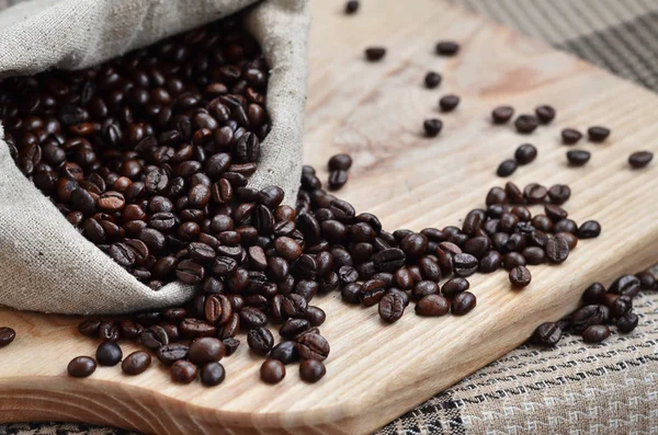 A full bag of brown coffee beans lies on a wooden surface. Attributes related to the preparation of natural coffee