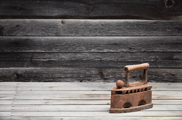 The heavy and rusty old coal iron lies on a wooden surface — Stock Photo, Image