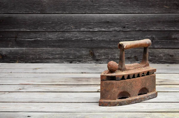 O ferro velho pesado e enferrujado do carvão encontra-se em uma superfície de madeira — Fotografia de Stock
