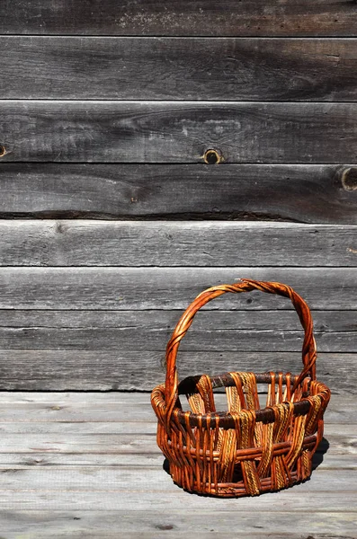 An empty wicker basket of wooden rods lies on a wooden surface
