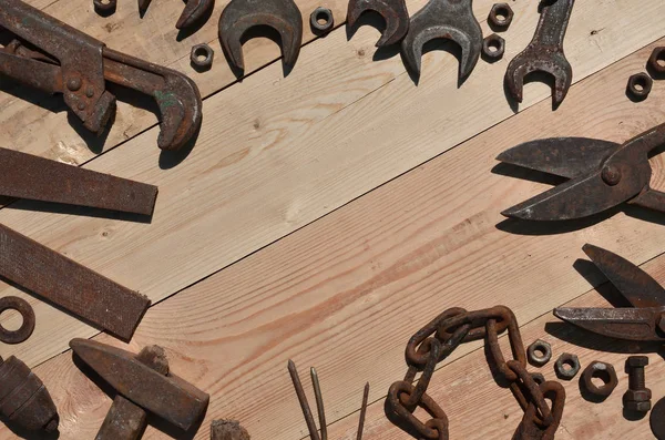 Un conjunto de herramientas viejas y oxidadas se encuentra en una mesa de madera en las obras —  Fotos de Stock