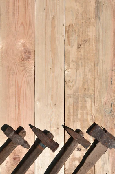 Unos cuantos martillos oxidados yacen sobre una mesa de madera en un taller —  Fotos de Stock