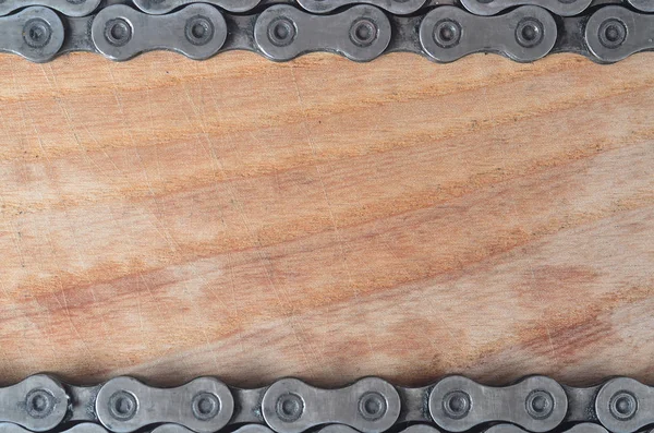 Background image of a chain from a mountain bike lying on a wooden table in a bicycle shop. One of the main elements of the transmission of torque on bikes and bicycles of various types