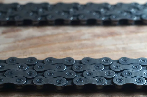 Background image of a chain from a mountain bike lying on a wooden table in a bicycle shop. One of the main elements of the transmission of torque on bikes and bicycles of various types