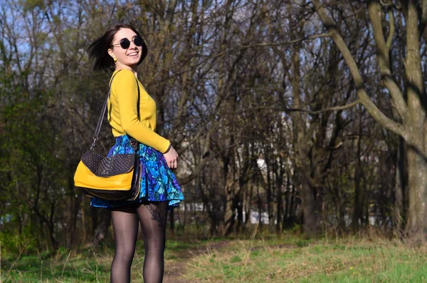 Une fille joyeuse dans un pull jaune vif marche à travers le sprin — Photo