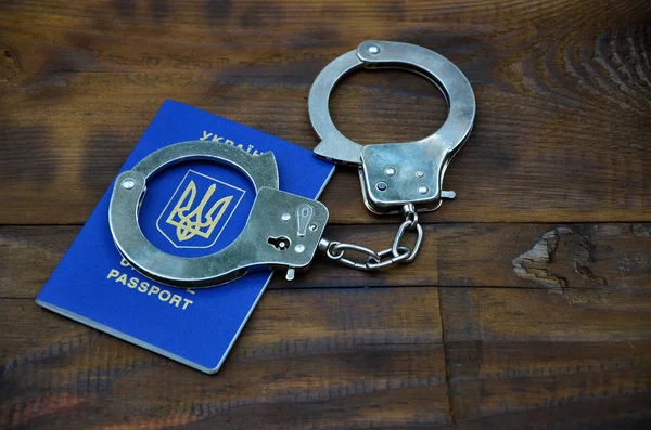 Ukrán útlevél a rendőrség bilincs fekszik egy fából készült asztal. — Stock Fotó