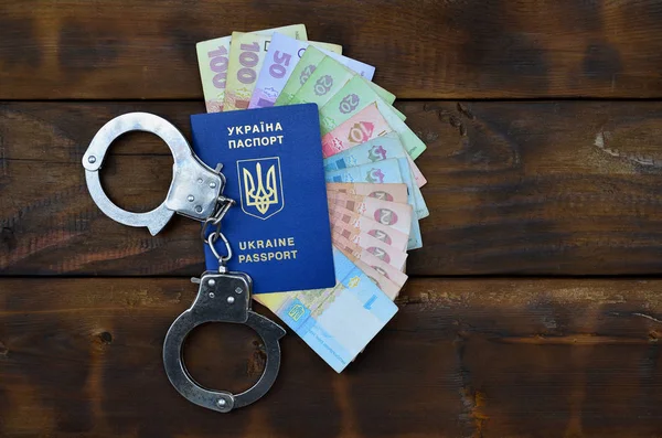 Una fotografía de un pasaporte extranjero ucraniano, una cierta cantidad de dinero ucraniano y esposas de la policía — Foto de Stock