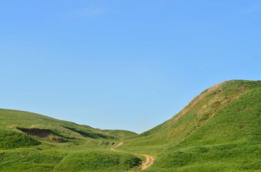 Harika bir yeşil dağlık arazi geçen bir çiğnenmiş yolu ile manzara. Fotoğraf güzel bir estetikle düzenlenmiş rahatlama alanı ince yolu ile