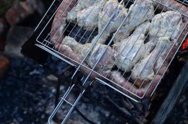 Şiş kebap üzerinden tavuk kanatları alanında yanmış. Klasik Barbekü açık havada. Kömür eti kızartma işlemi