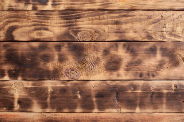 The texture of the scorched wooden wall. Wall of smooth orange long wooden boards with a specific black texture of frying