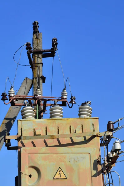 Oude en verouderde elektrische transformator tegen de achtergrond van een wolkenloze blauwe hemel — Stockfoto