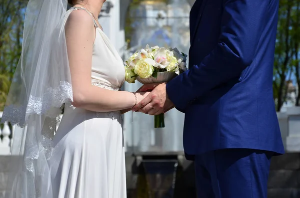 The newlywed couple is holding a beautiful wedding bouquet. Classical wedding photography, symbolizing unity, love and the creation of a new family