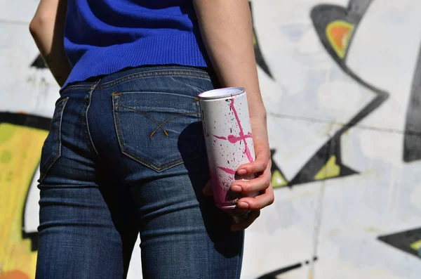 Foto de una chica con latas de pintura en aerosol en las manos sobre un fondo de pared de graffiti — Foto de Stock