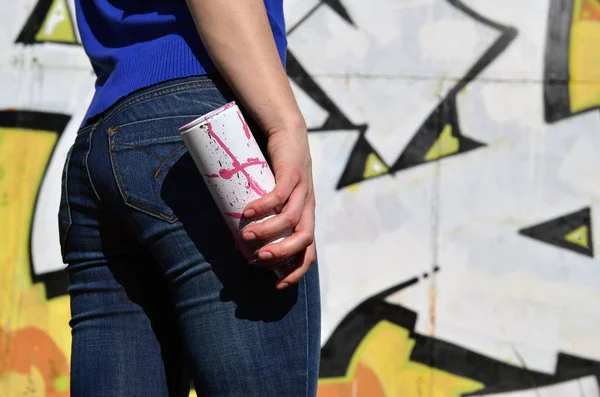 Фото девушки с канистрами аэрозольной краски в руках на фоне стены граффити — стоковое фото