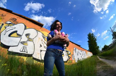 Siyah saçlı ve piercing ile duygusal bir genç kız portresi. Sprey boya... kutularını graffiti duvar arka plan üzerinde elinde bir kızla bir geniş açı fotoğraf. Bir balıkgözü lens modern bir portresi