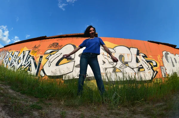 Fénykép egy lányt aeroszolos festékkel doboz, kezében a graffiti fal háttér — Stock Fotó