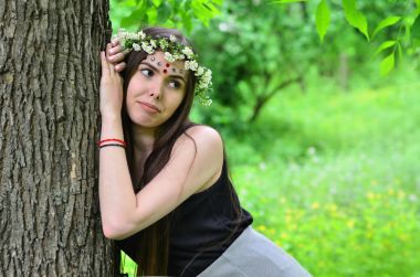 Çiçek çelenk başında ve alnındaki parlak süsler ile duygusal bir genç kız portresi