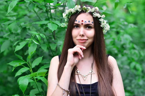 Portrait d'une jeune fille émotionnelle avec une couronne florale sur la tête et des ornements brillants sur le front — Photo