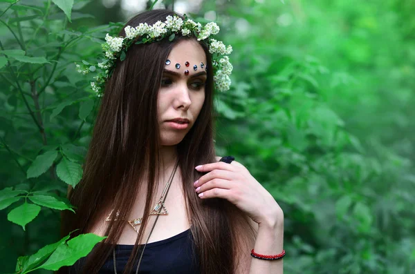 Portrait of an emotional young girl with a floral wreath on her head and shiny ornaments on her forehead — Stock Photo, Image