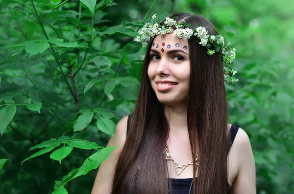 Portrait d'une jeune fille émotionnelle avec une couronne florale sur la tête et des ornements brillants sur le front — Photo