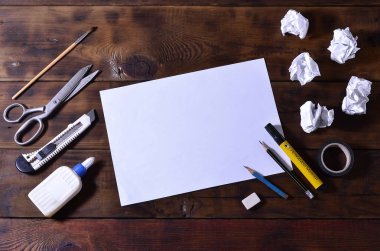 Bir okul ya da office natürmort birçok ofis malzemeleri ve Kağıt beyaz boş bir levha ile. Okul yalan üzerine kahverengi ahşap arka plan sağlar. Metin için yer