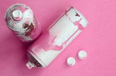 Some used pink aerosol spray cans and nozzles with paint drips lies on a blanket of soft and furry light pink fleece fabric. Classic female design color. Graffiti hooliganism concept clipart