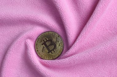 Altın bitcoin yumuşak ve kabarık hafif pembe Polar kumaş çok sayıda kabartma kıvrımları ile yapılmış bir battaniye yatıyor. Kıvrımları şeklinde bir ekran kartı soğutucu fan benzer