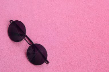 Şık siyah güneş gözlüğü gözlük yalanlar üzerine bir battaniye yumuşak ve kabarık hafif pembe Polar kumaştan yapılmış yuvarlak. Kadın renklerde şık arka plan resmi