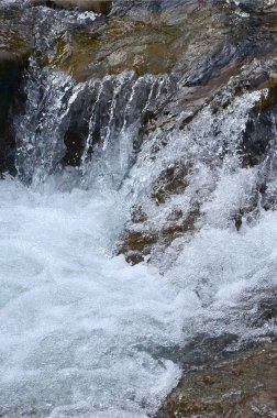 Yakın çekim görüntü dağ taş arasında su kısa streams şeklinde küçük bir vahşi şelale