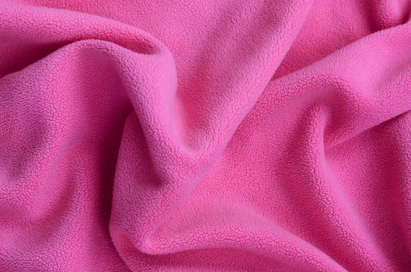 The blanket of furry pink fleece fabric. A background of light pink soft plush fleece material with a lot of relief folds