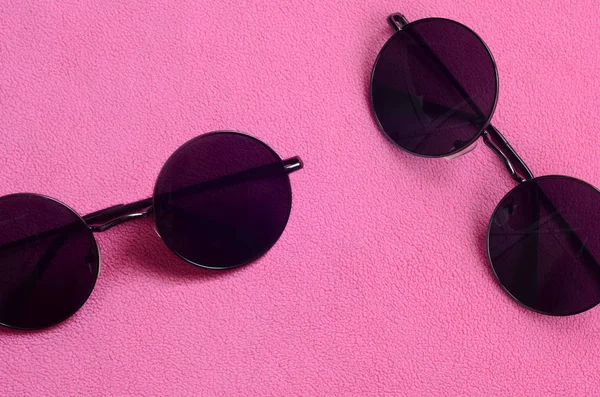 İle iki şık siyah güneş gözlüğü gözlük yalanlar üzerine bir battaniye yumuşak ve kabarık hafif pembe Polar kumaştan yapılmış yuvarlak. Kadın renklerde şık arka plan resmi