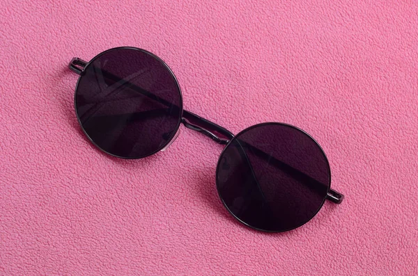 Şık siyah güneş gözlüğü gözlük yalanlar üzerine bir battaniye yumuşak ve kabarık hafif pembe Polar kumaştan yapılmış yuvarlak. Kadın renklerde şık arka plan resmi