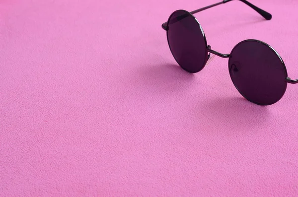 Şık siyah güneş gözlüğü gözlük yalanlar üzerine bir battaniye yumuşak ve kabarık hafif pembe Polar kumaştan yapılmış yuvarlak. Kadın renklerde şık arka plan resmi