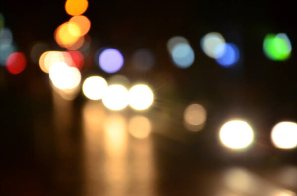 Blurred night scene of traffic on the roadway. Defocused image of cars traveling with luminous headlights. Bokeh Art