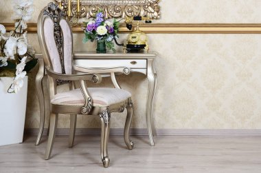 Bir sandalye ve bir masa üzerine retro bir iç bir parçası olan telefon ve kenarındaki çiçek dolu vazolar yer alır