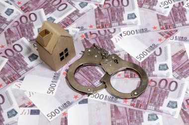 Emlak ile aldatmaca. Hile ne zaman satın almak veya bir ev kiralamak. Aldatma için ceza. Birçok 500 mor euro banknot üzerinde kelepçe ile bir oyuncak ev