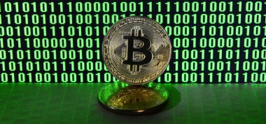 Bitcoins bir çift yatıyor bir karton yüzeyi parlak yeşil sıfır ve bir çift değişkenli bir kod resmeden bir monitör arka plan üzerinde siyah bir zemin üzerine birimleri. Düşük anahtar aydınlatma